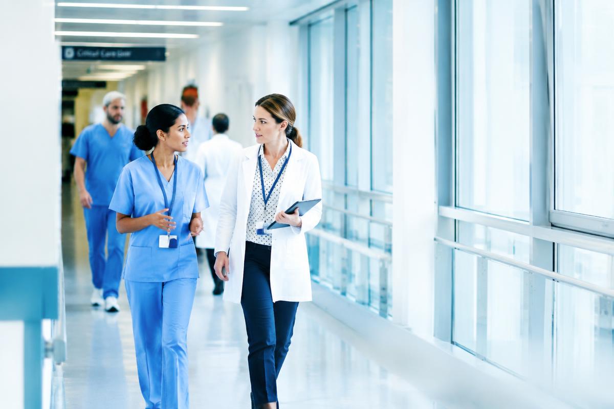 Clinicians walking through a bright modern hospital corridor