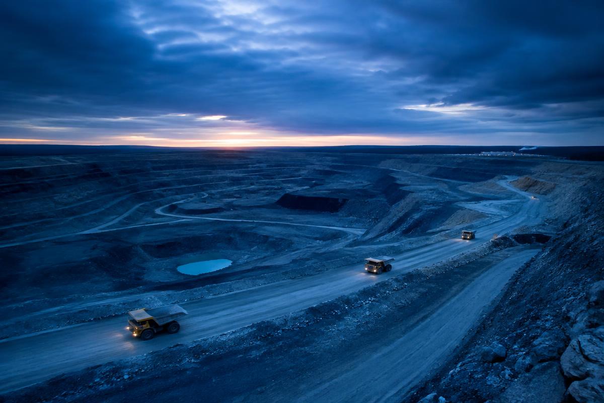 Aerial view of an open-pit mine with haul trucks at dusk